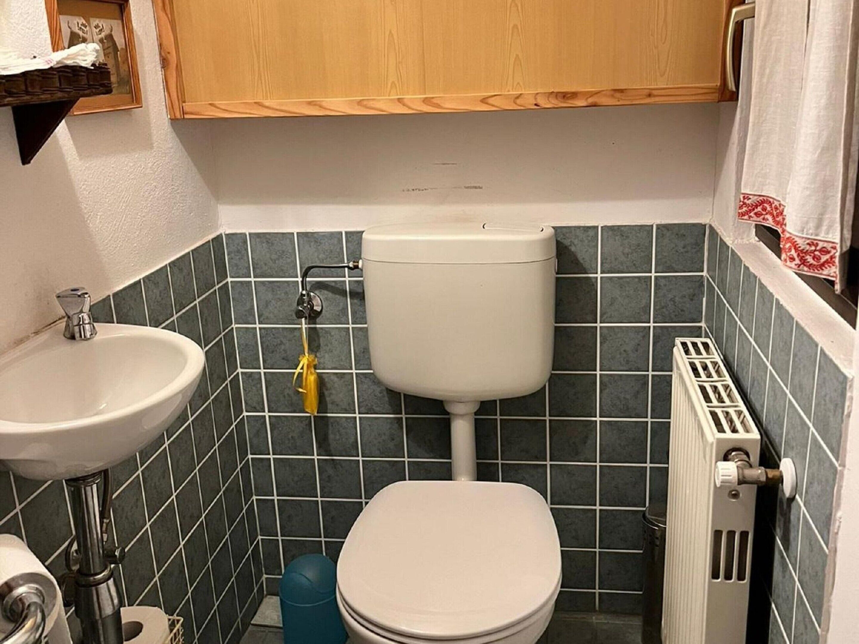 A small bathroom with a toilet, sink, and radiator.
