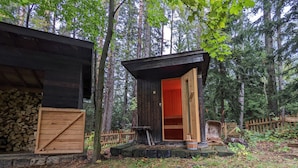 A rustic cabin with a wooden door open, surrounded by a wooden fence and dense forest. - Holiday Home in Edlitz Near Ski Slopes (Edlitz)