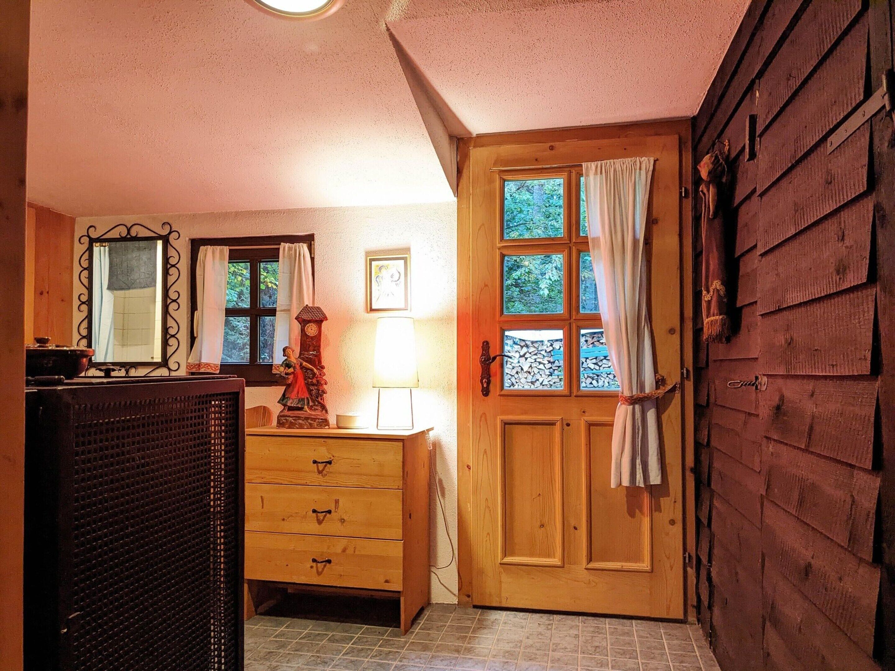A wooden door with a window, a mirror, a dresser, and a lamp.