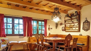 A cozy dining area with wooden furniture, a chandelier, and a window with red curtains. - Holiday Home in Edlitz Near Ski Slopes (Edlitz)