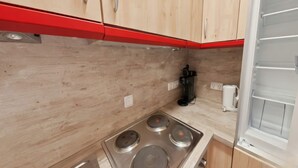 A kitchen with wooden cabinets, a gas stove, and a coffee maker. - Appartement Martin mit Wellnessbereich (Freyung)
