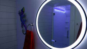 A bathroom with a round mirror, a towel rack with a towel, and a decorative wall piece.
