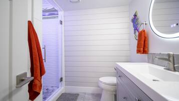 Une salle de bain avec douche, toilettes et lavabo.