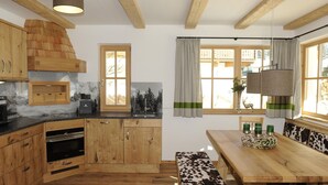 A kitchen with wooden cabinets, a built-in oven, and a dining area with a bench and table.