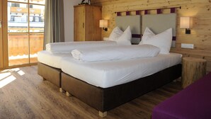 Un lit double avec du linge de lit blanc, une tête de lit en bois et deux lampes de chevet.