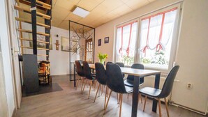 A dining area with a wooden table and chairs, a staircase, and a window with curtains. - Cozy Holiday Home With Terrace and Garden (Grossbreitenbach)