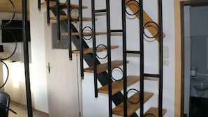 A staircase with wooden steps and black metal railings, leading to a landing with a door. - Cozy Holiday Home With Terrace and Garden (Grossbreitenbach)