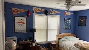 Een slaapkamer met een bed, een bureau, een wereldbol en sportbanners aan de muur.