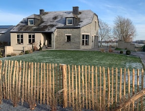 A two-story stone house with a sloped roof, a fenced yard, and a clear sky. - Elegant Family Stay, Wallonia (Bertrix)