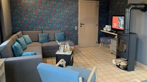 Una sala de estar con sofá, televisor, chimenea y puerta.