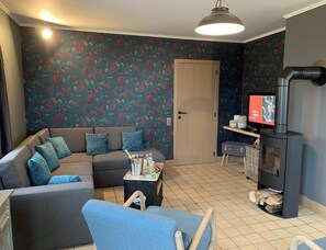 A living room with a sofa, a television, a fireplace, and a door.