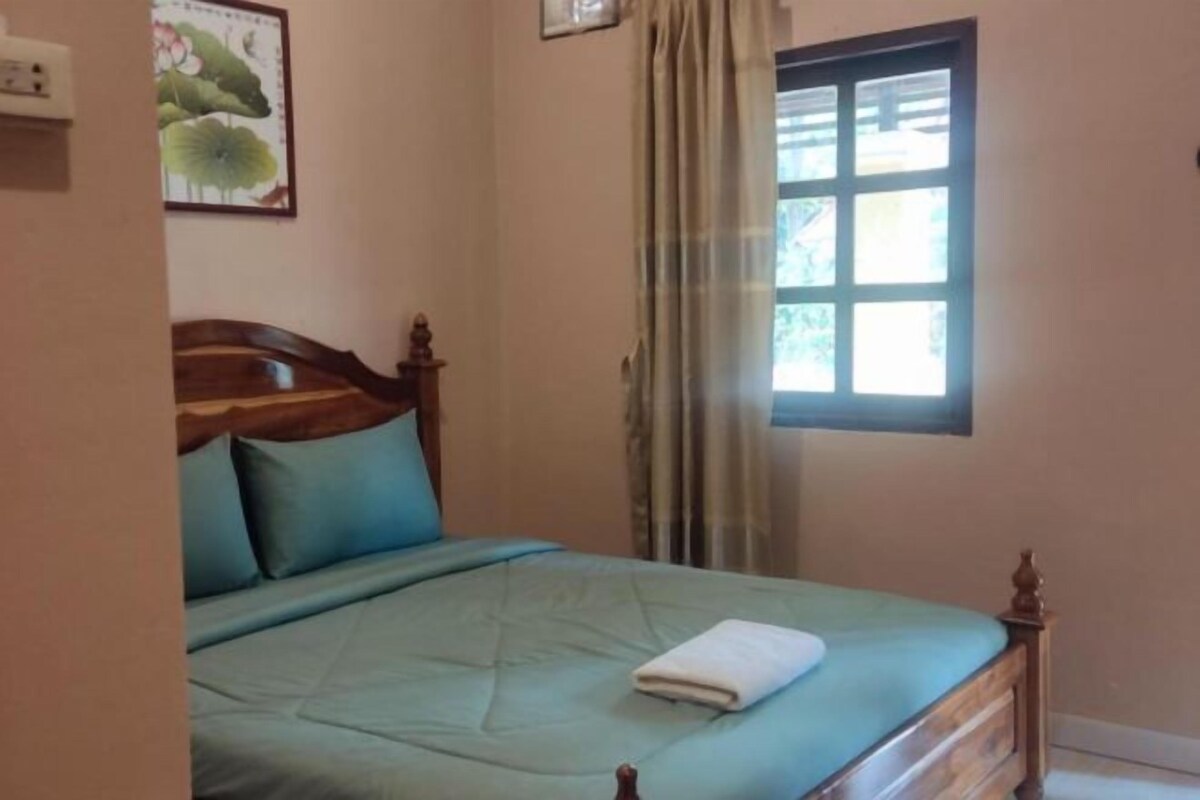 Un dormitorio con una cama de madera, un ventanal con cortinas y un interruptor de luz en la pared.