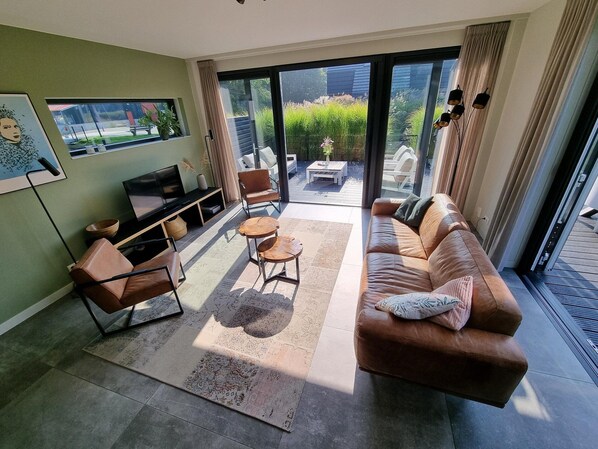 A modern living room with a sofa, chairs, a coffee table, and a TV.