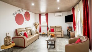 Ein modernes Wohnzimmer mit einer Couch, Sesseln, einem Couchtisch und einem Fernseher.