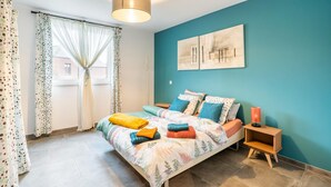 Ein Schlafzimmer mit einem Bett, Vorhängen, einem Nachttisch und einem Wandbild.