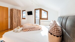 Une chambre à coucher avec un lit, une télévision, une fenêtre et une porte.