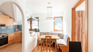 Une cuisine compacte avec des meubles en bois, un four encastré et un coin repas comprenant une table et des chaises.