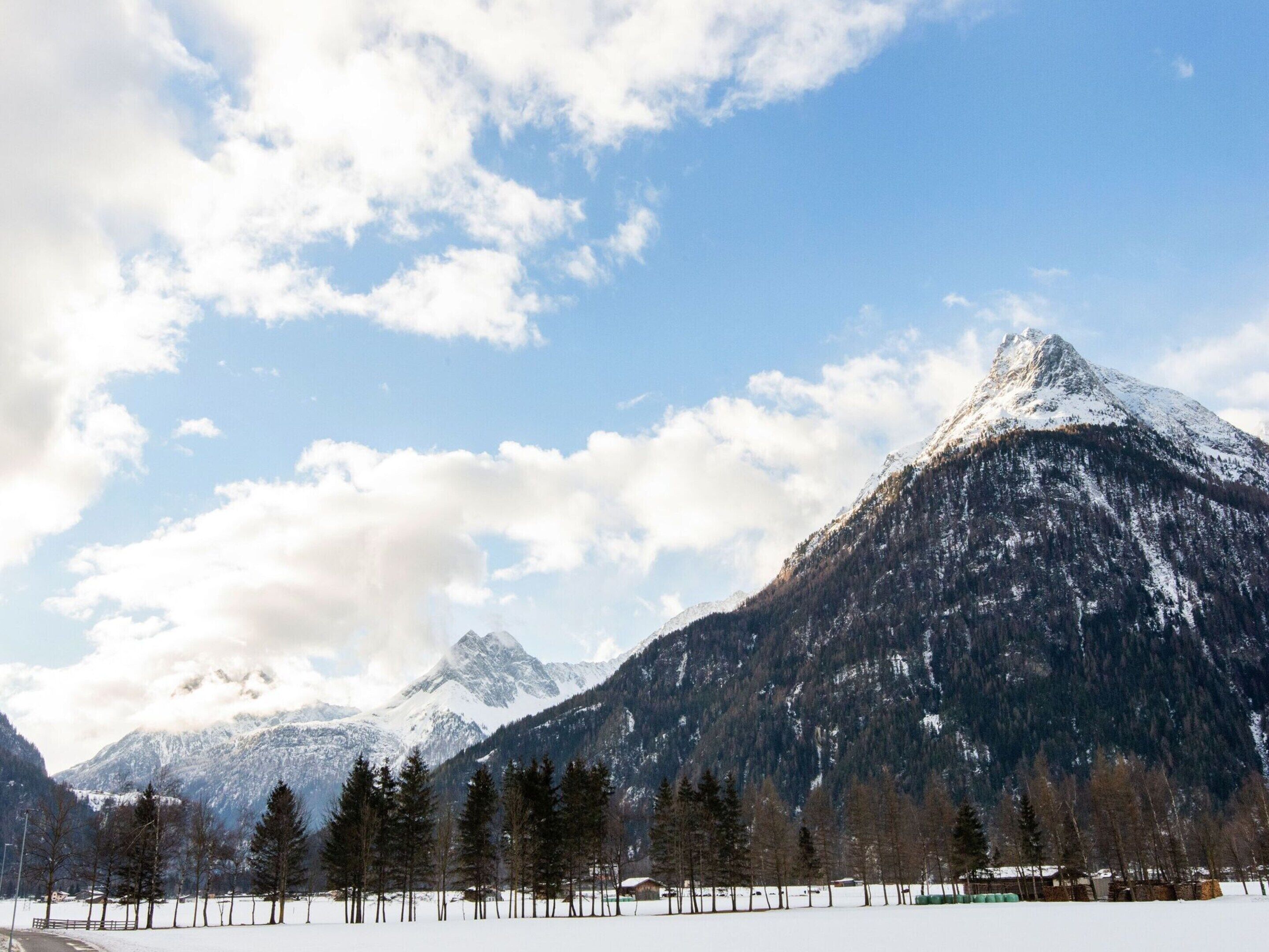 A mountainous landscape with snow-covered peaks and a clear sky.