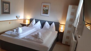 A neatly made bed with white linens and towels, a headboard, bedside lamps, a framed picture on the wall, and a radiator. - Pretty Apartment in Mittersill With a View (Mittersill)