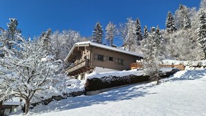 A chalet with a balcony, surrounded by snow-covered trees and a clear blue sky. - Pretty Apartment in Mittersill With a View (Mittersill)