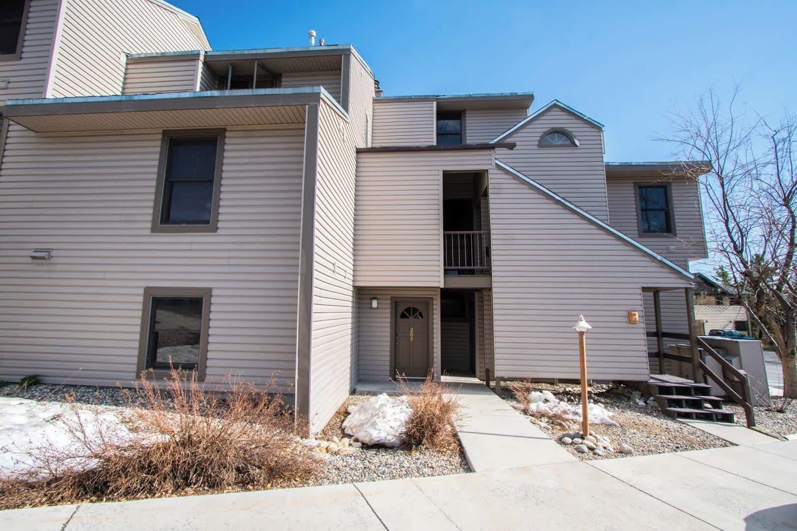 A multi-story residential building with a central entrance, a small balcony, and a staircase leading to an upper level.