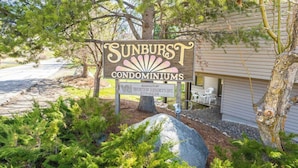Une enseigne pour le complexe d’appartements Sunburst, avec un gros rocher et de la verdure au premier plan.
