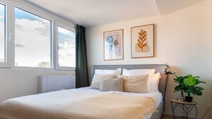 A bedroom with a bed, a window, a plant, and two framed pictures on the wall. - Suite in Vrouwenpolder Near North Sea Beach (Vrouwenpolder)