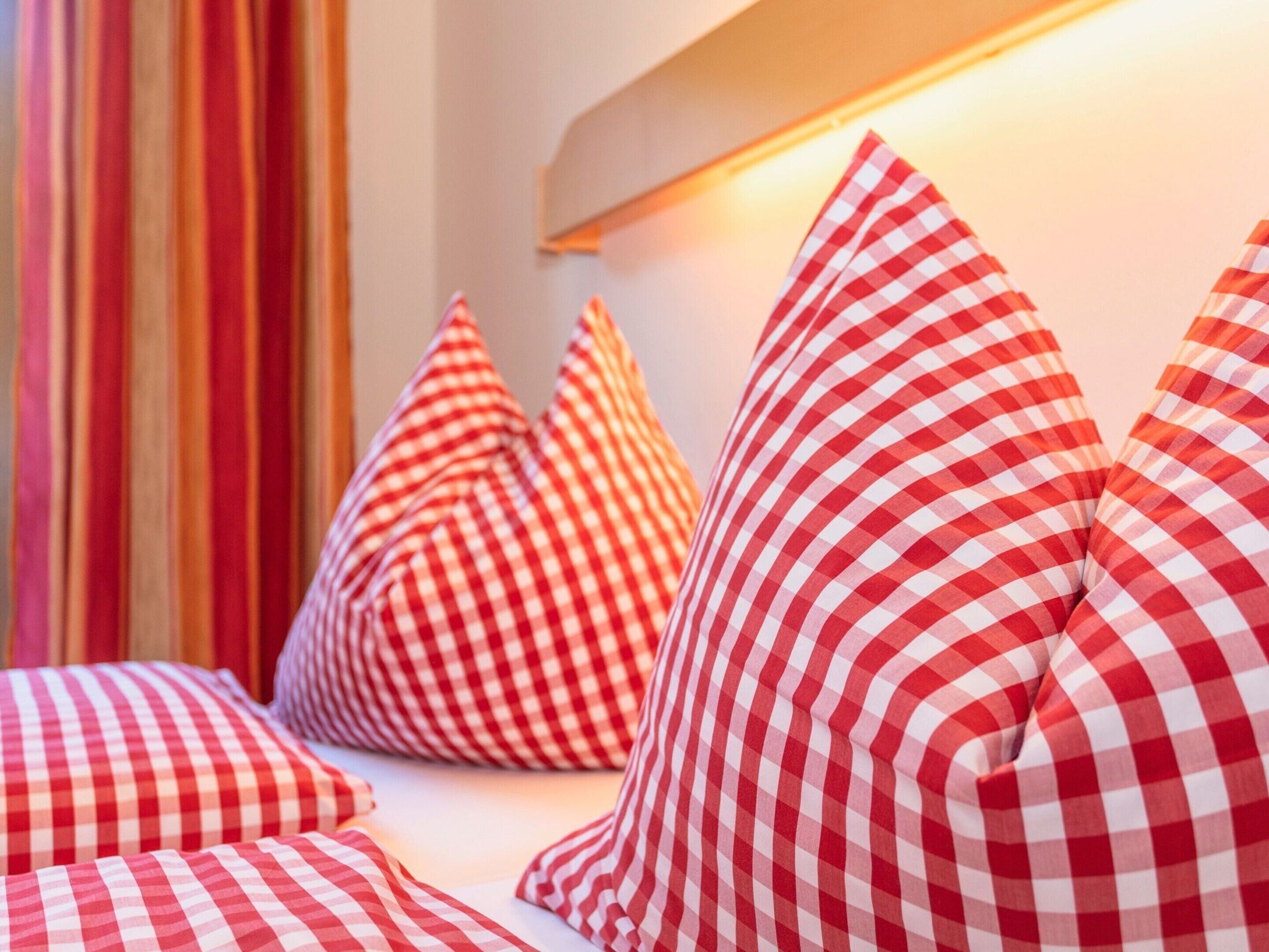 A room with a bed, pillows, and a wall-mounted light.