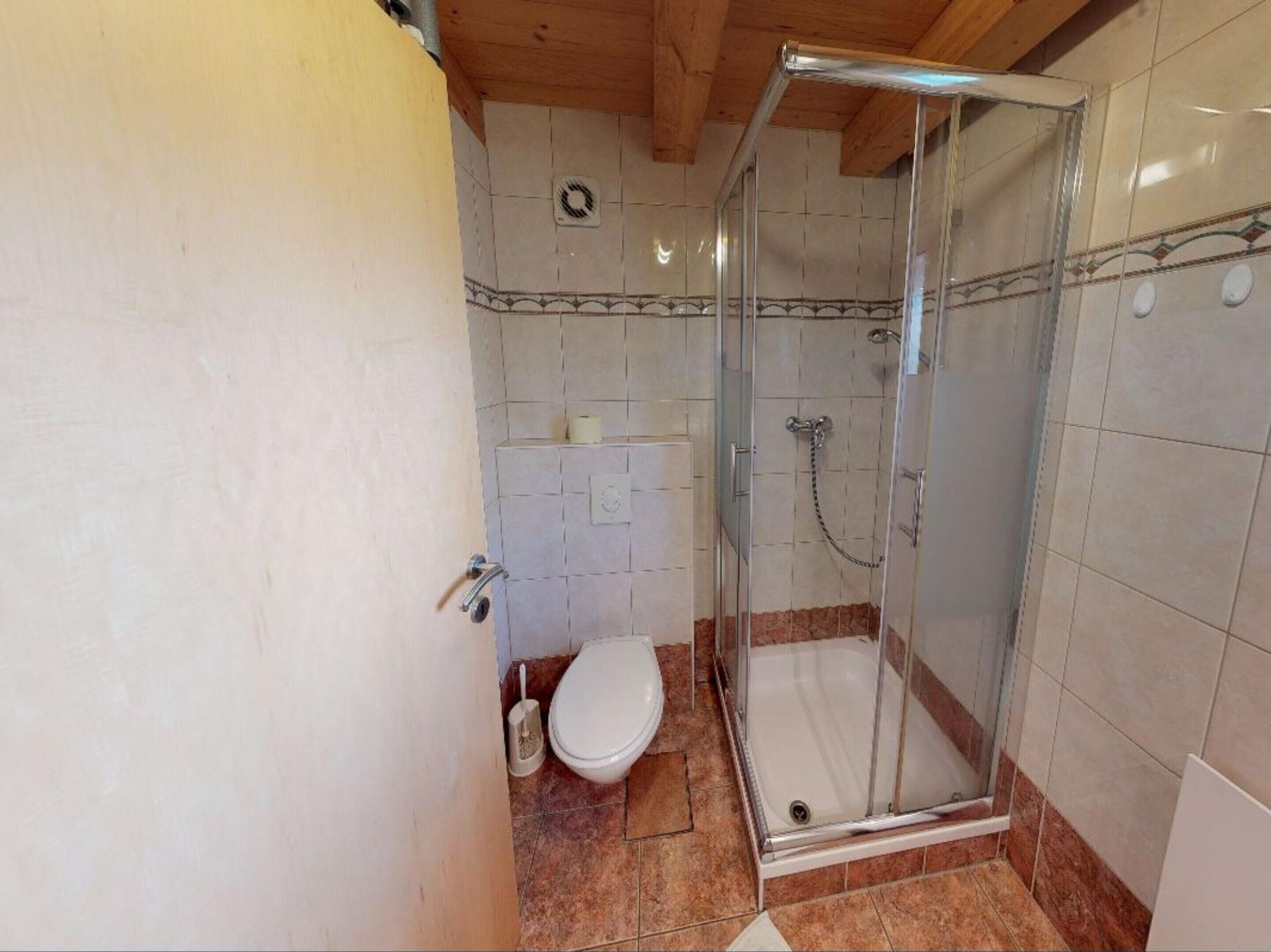 A small bathroom with a shower, toilet, and a towel rack.