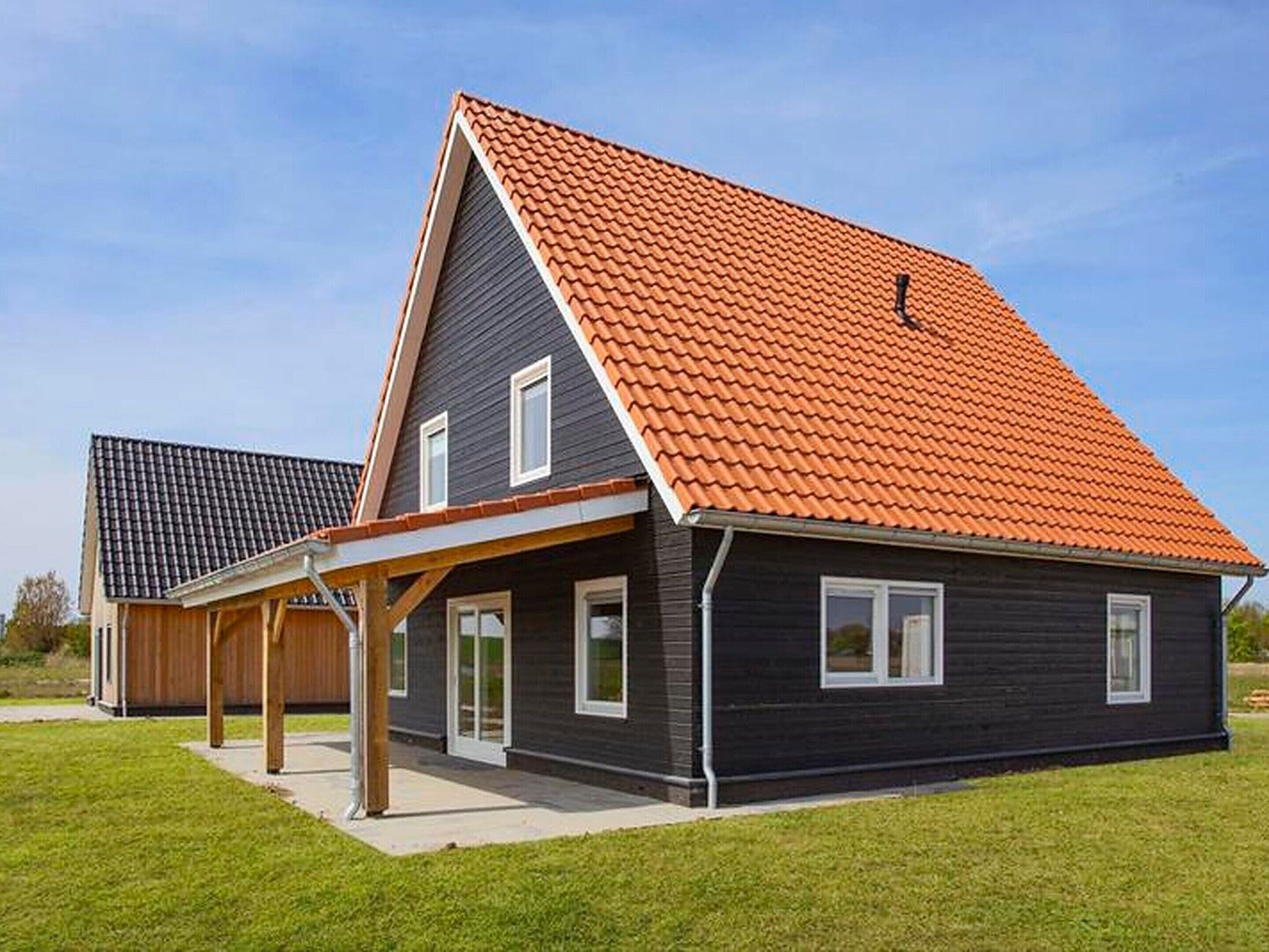 A modern two-story house with a dark exterior and a red-tiled roof.