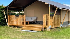Ett takförsett utomhusområde med sittplatser, en soffa och ett bord, omgivet av trästaket.