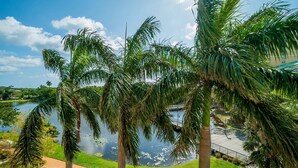 A view of a lake with palm trees and a deck overlooking the water. - Nautical Beach Suite - Casa Costa 314S - 2 Beds, Pools, Beach & Dog Friendly (Boynton Beach)