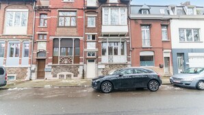 A row of townhouses with a garage door, a stone facade, and a clear sky. - Nice Apartment in Liege With Parking (Liege)
