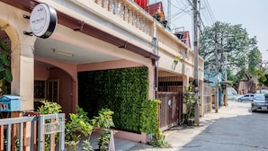 A residential building with a balcony, potted plants, and a sign indicating a business. - Baan Mee Suk Ayutthaya (Ayutthaya)