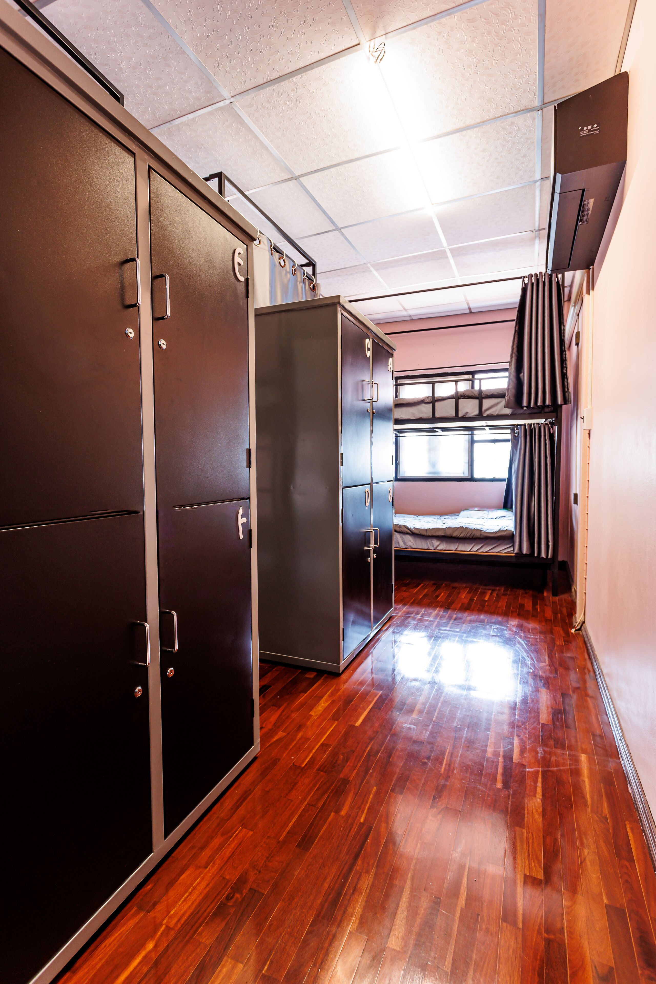 A compact room with a bunk bed, a wardrobe, and a small window.