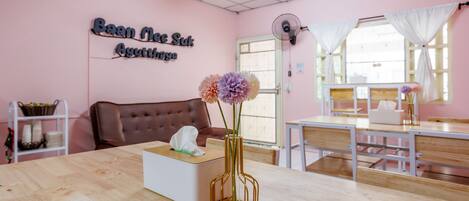 A room with a wooden table, a vase with flowers, a couch, and a sign on the wall.