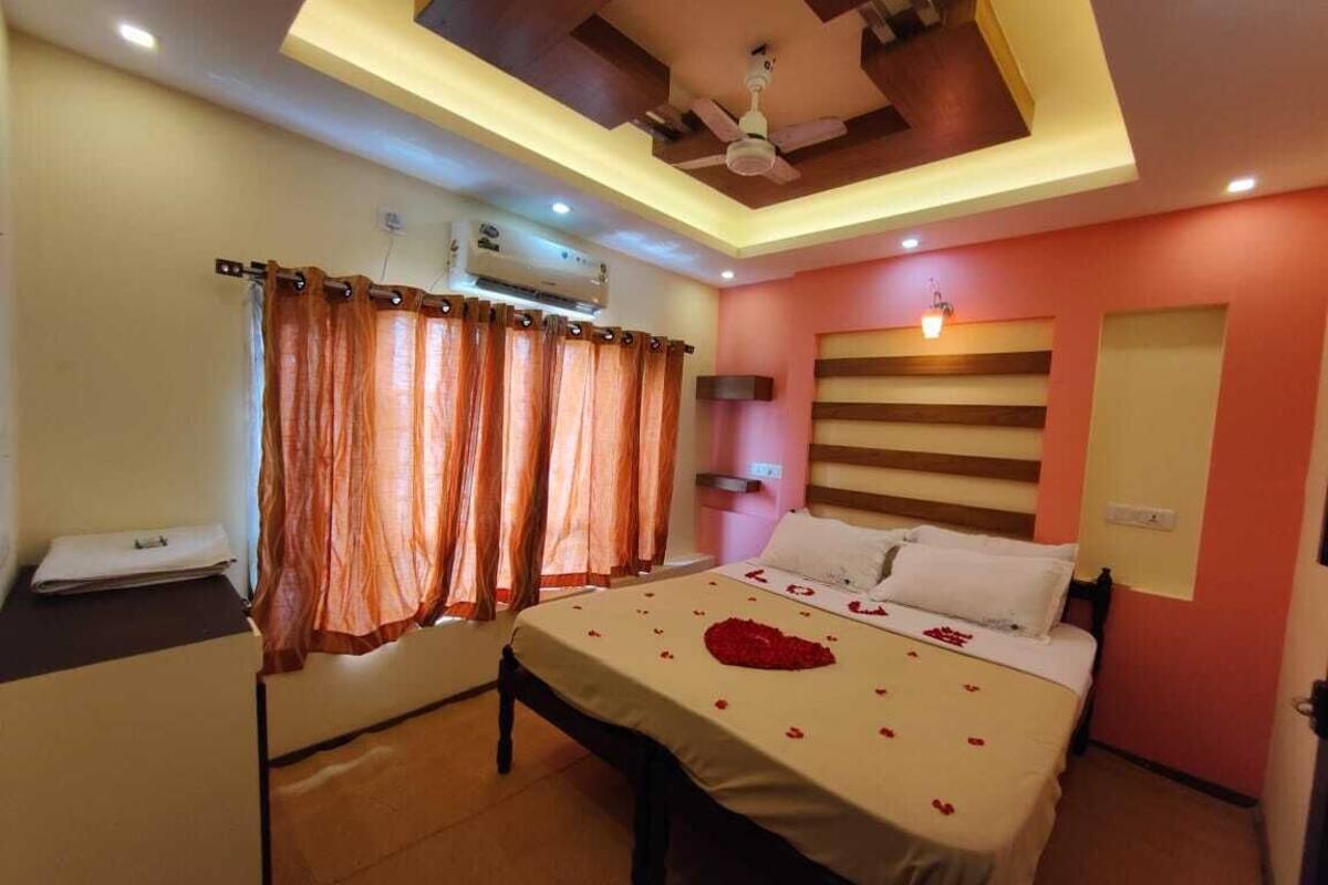 Quarto com cama, escrivaninha, ventilador de teto e ar-condicionado fixado na parede.
