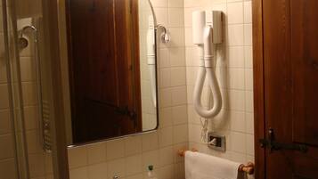 Casa de banho com lavatório, espelho e secador de cabelo fixado na parede.