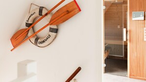 A wall-mounted life preserver with two wooden paddles and the text "Swanneblom" and "Earnewald" on it. - Bungalow With Sauna & Nature (Earnewald)