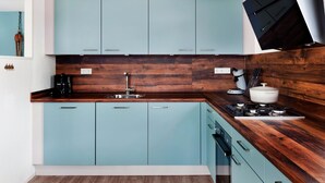 A modern kitchen with teal cabinets, a wooden countertop, and a built-in stove. - Bungalow With Sauna & Nature (Earnewald)