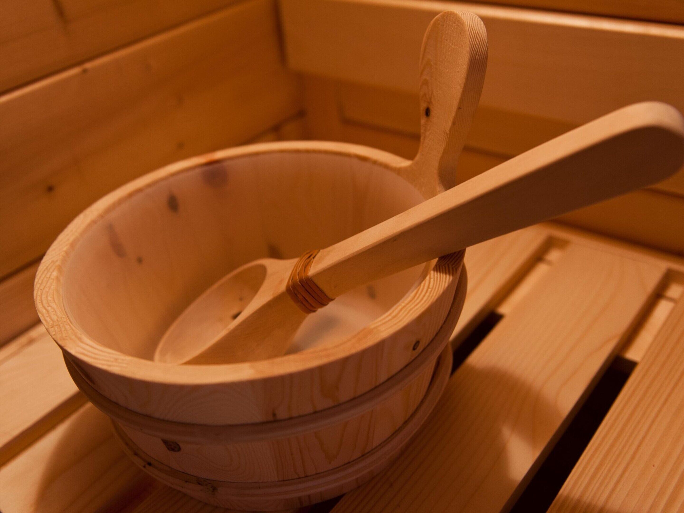 A wooden bowl with a spoon inside, placed on a wooden surface.