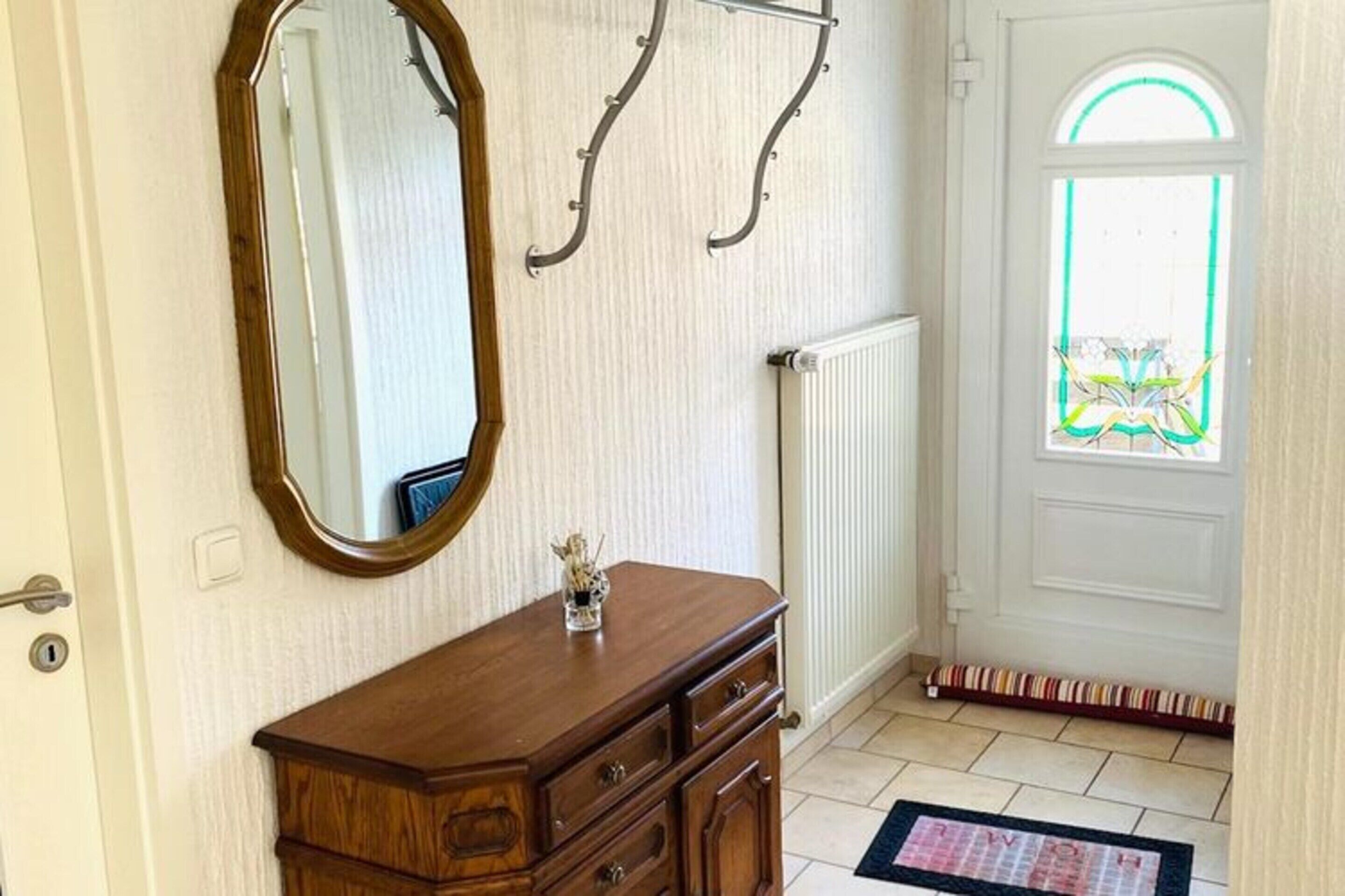 A room with a wooden dresser, a large mirror, and a radiator.