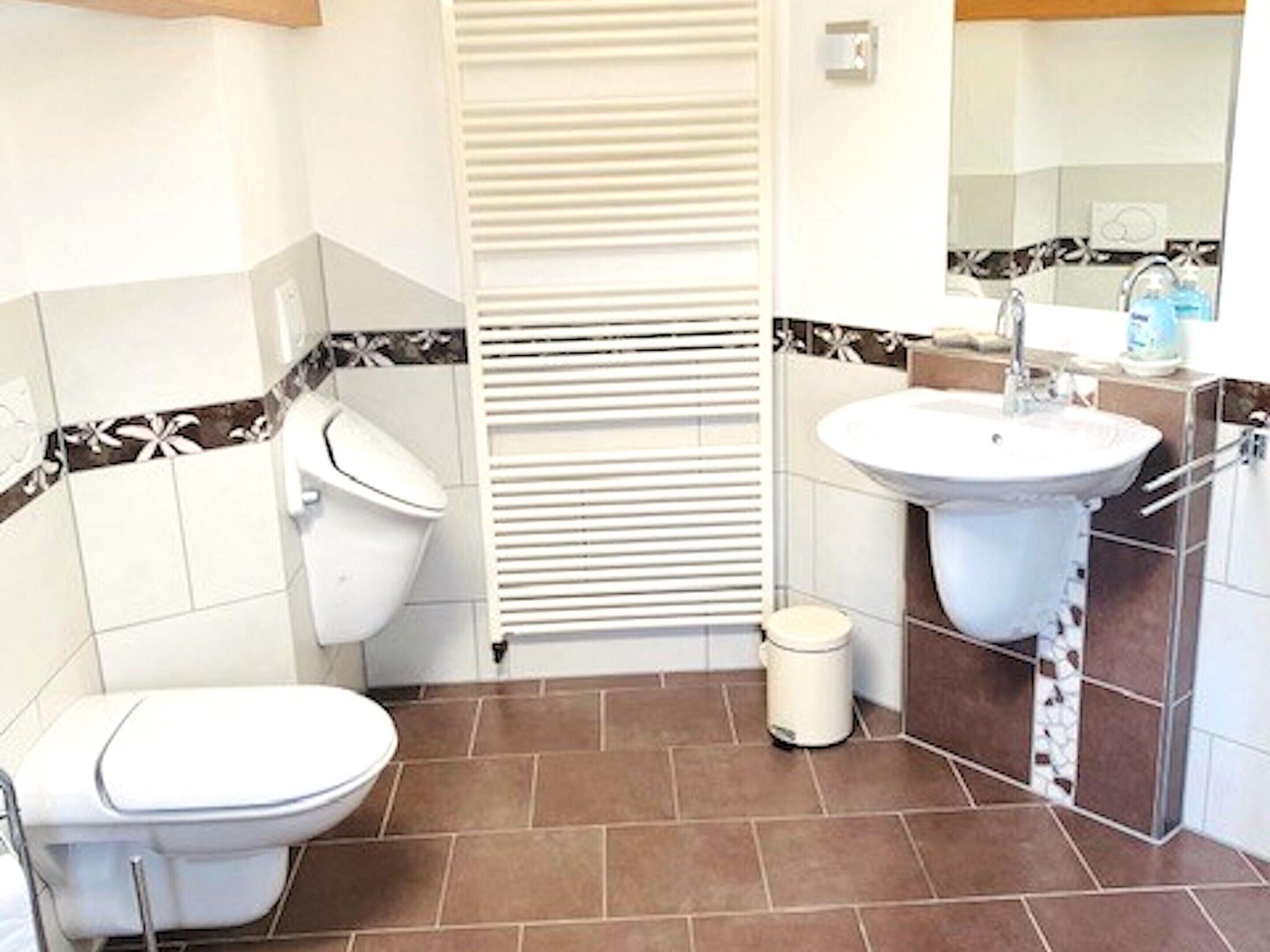 Een badkamer met toilet, wastafel en een vuilnisbak.
