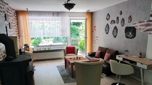 A modern living room with a sofa, coffee table, and a dining area with a desk. - Delightful Apartment in Goslar With Garden and Terrace (Goslar)