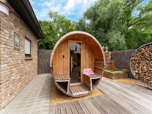 A wooden sauna structure with a bench inside, a door, and a small bench outside. - Restful Holiday Home in Koksijde With Hot Tub and Sauna (Koksijde)
