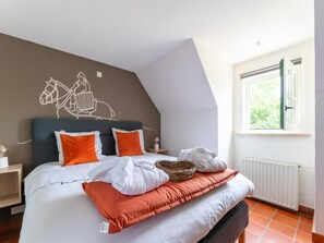 A bedroom with a bed, pillows, a wall mural, a window, and a radiator.