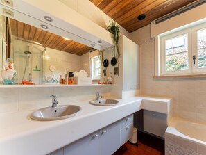 A modern bathroom with two sinks, a large mirror, and a window.