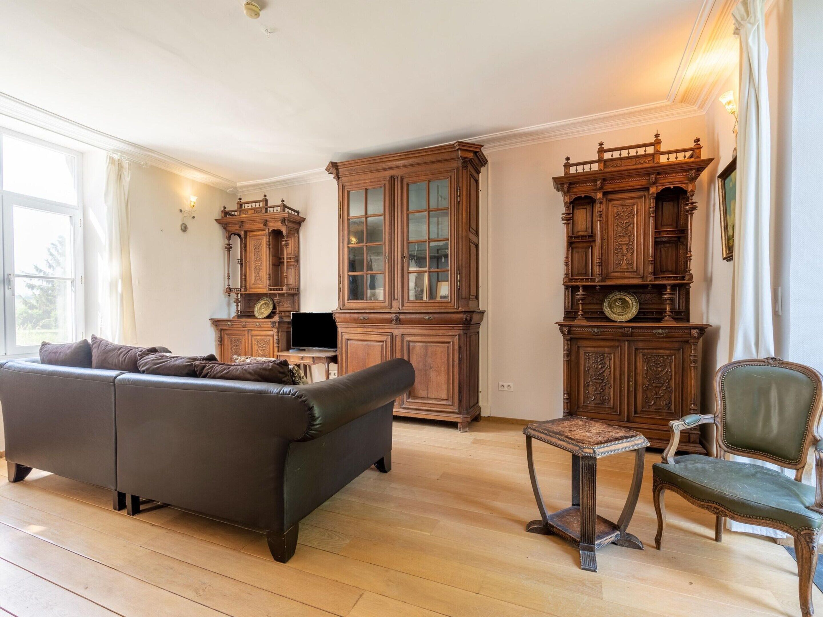 A room with a leather sofa, wooden cabinets, and a green armchair.