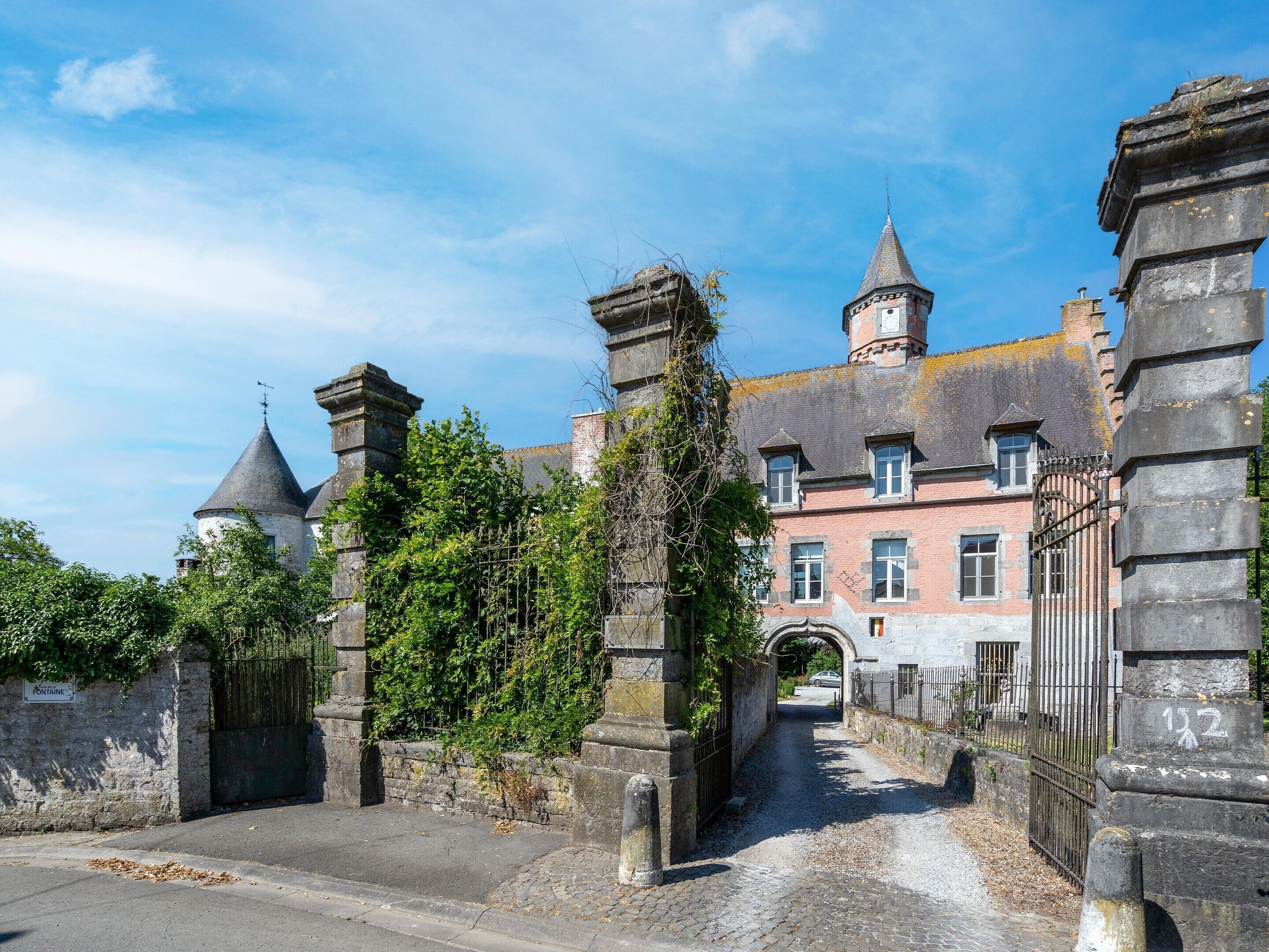 A historic building with a stone gate, a tower, and a paved pathway leading to the entrance.