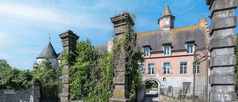 Un edificio histórico con una puerta de piedra, una torre y un camino empedrado que lleva a la entrada.